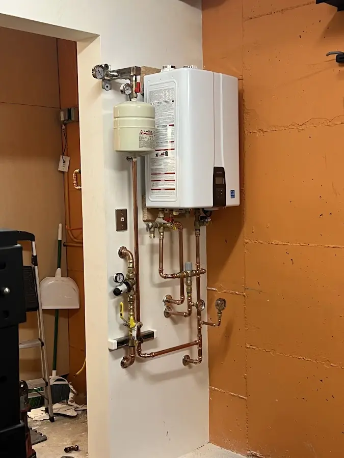 Plumbing technician inspecting water heater connections in West Gardiner